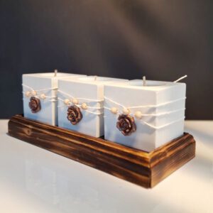 Zestaw trzech białych świeczników na tealighty w ozdobnej drewnianej podstawce z dekoracyjnymi frezami.