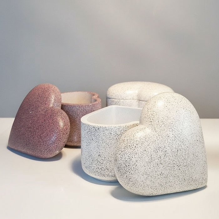 Betonowe serca w kolorze różowym i białym jako pojemniki dekoracyjne.